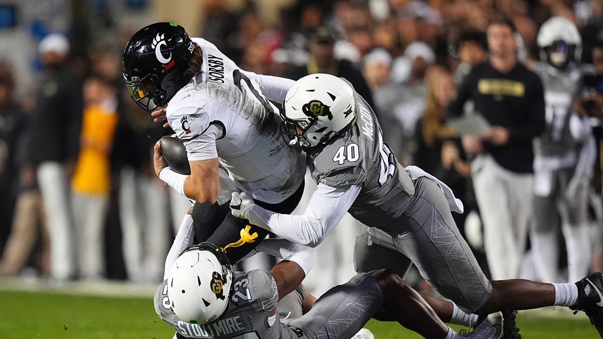 Colorado Buffaloes defensive end Taje McCoy (40) and safety Carter Stoutmire (23) tackle Cincinnati Bearcats quarterback Brendan Sorsby (2) in the fourth quarter at Folsom Field.