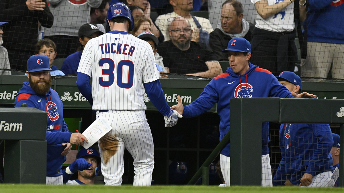 Chicago Cubs outfielder Kyle Tucker (30) high fives Chicago Cubs manager Craig Counsell (11) after scoring during the first inning against the Los Angeles Dodgers at Wrigley Field.
