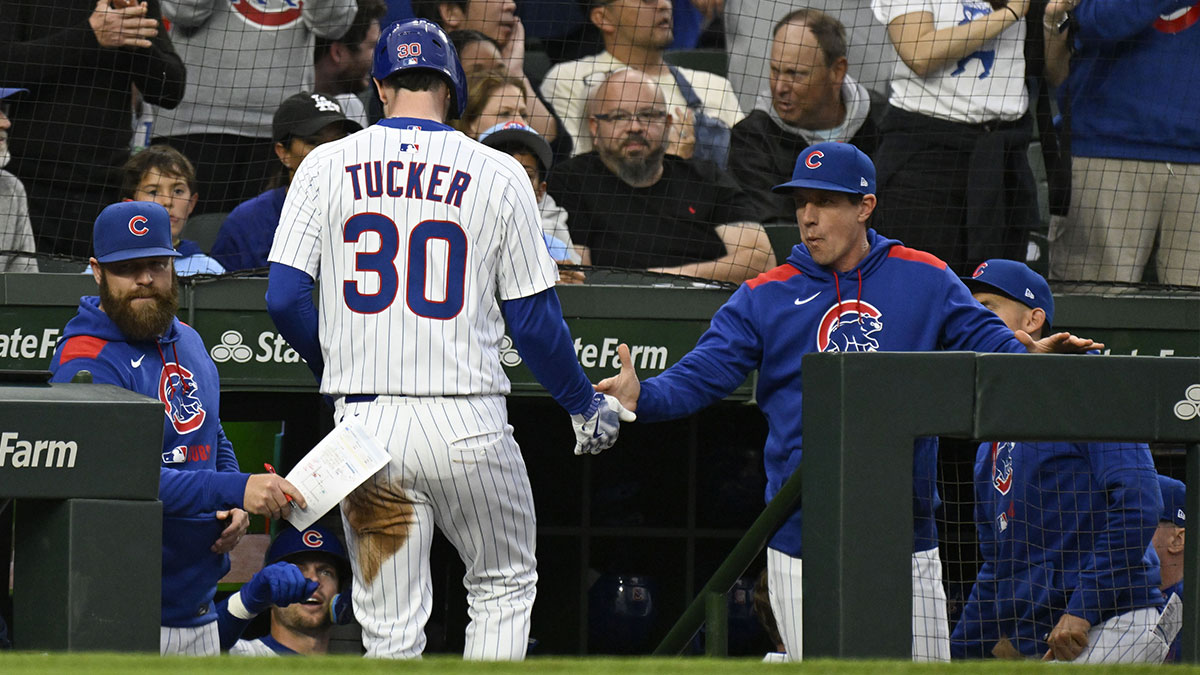 Chicago Cubs outfielder Kyle Tucker (30) high fives Chicago Cubs manager Craig Counsell (11) after scoring during the first inning against the Los Angeles Dodgers at Wrigley Field.