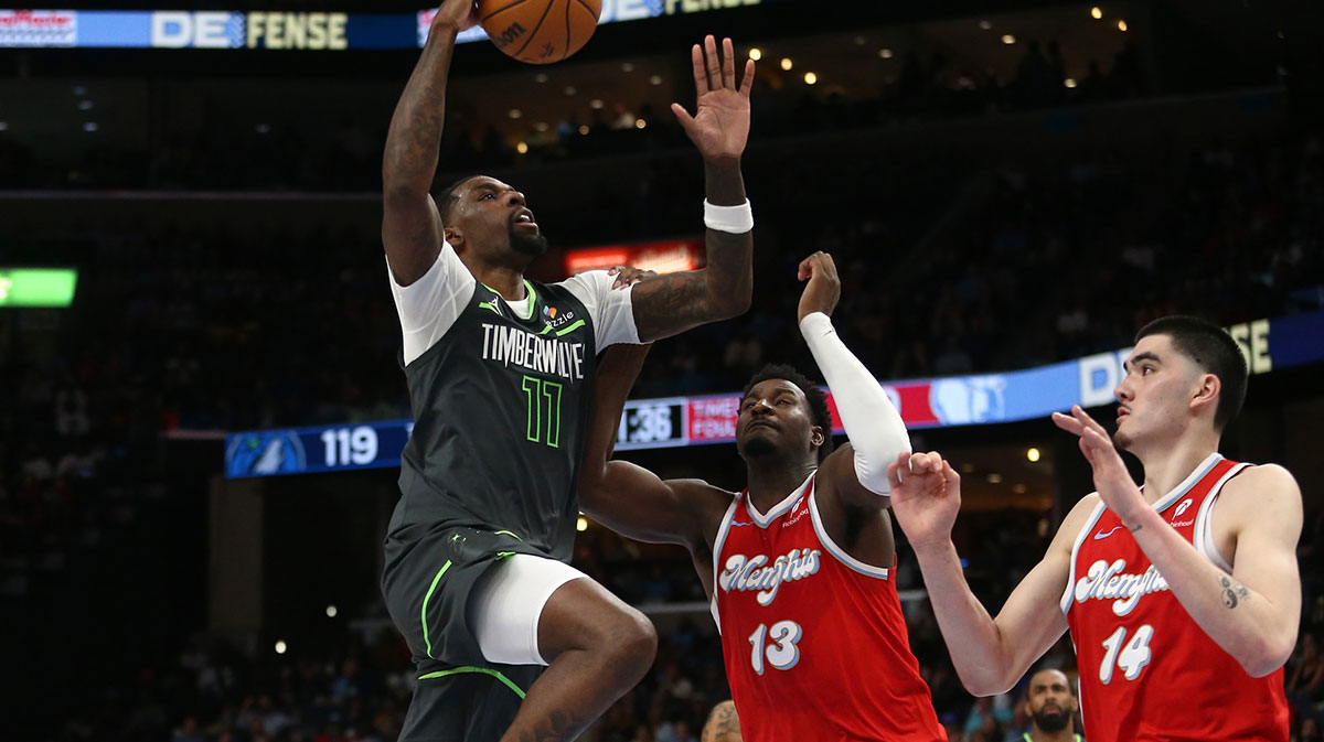 Minnesota Timberwolves center Naz Reid (11) drives to the basket as Memphis Grizzlies forward Jaren Jackson Jr. (13) and center Zach Edey (14) defend during the fourth quarter at FedExForum.