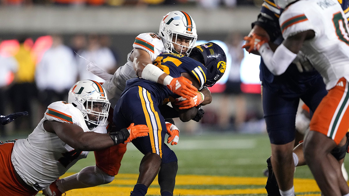 Miami Hurricanes linebacker Raul Aguirre Jr. (center left) and defensive lineman Rueben Bain Jr. (left) tackle California Golden Bears running back Jaivian Thomas (center right) during the fourth quarter at California Memorial Stadium. Mandatory Credit: Darren Yamashita-Imagn Images