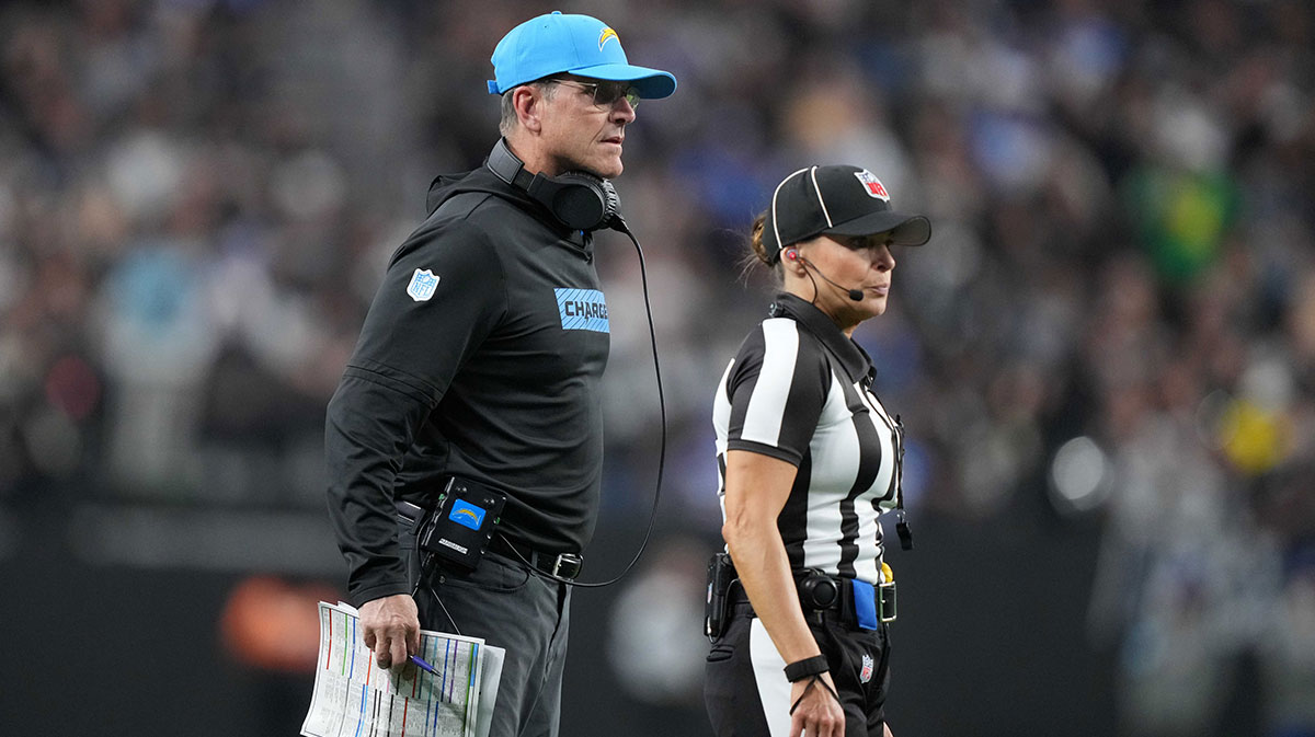 NFL female line judge referee Robin DeLorenzo (134) and Los Angeles Chargers coach Jim Harbaugh watch from the sidelines in the second half against the Las Vegas Raiders at Allegiant Stadium.