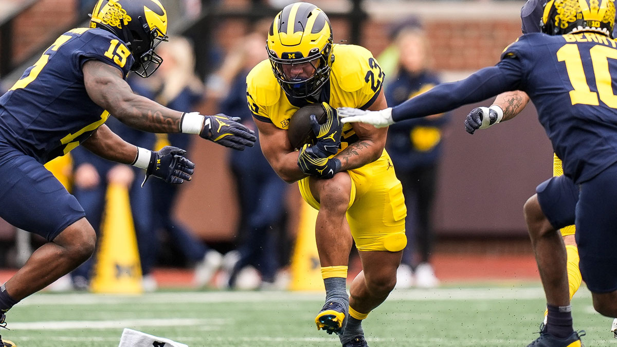 Team Maize running back Jordan Marshall (23) runs against Team Blue linebacker Ernest Hausmann (15) and defensive back Zeke Berry (10) during the first half of the spring game at Michigan Stadium