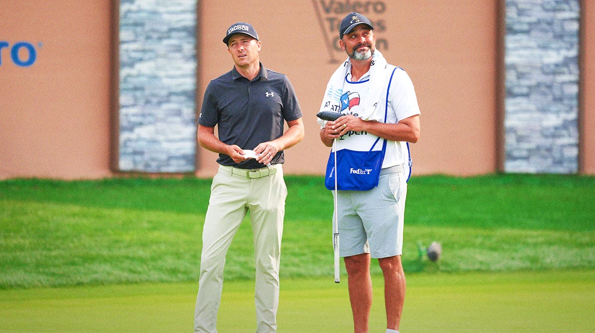 Jordan Spieth (left) and his caddie look to the skies as the sun breaks through on the 16th green during the second round of the Valero Texas Open
