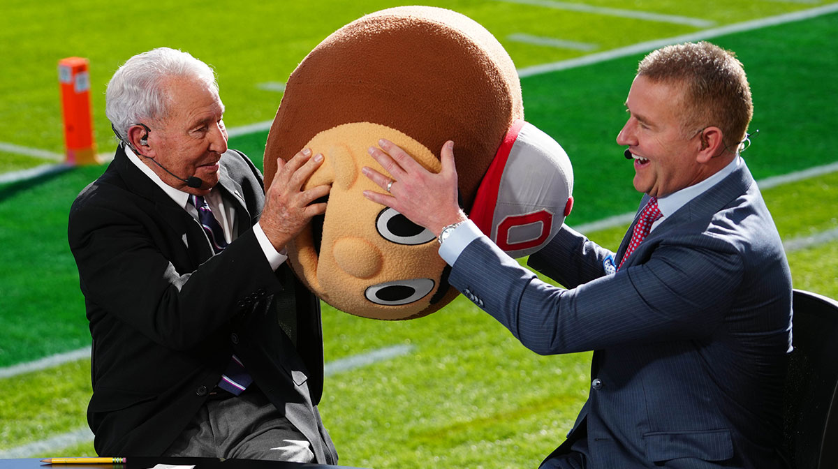 Lee Corso (left) wears a Buckeyes mascot head as Kirk Herbstreit watches at Rose Bowl Stadium.