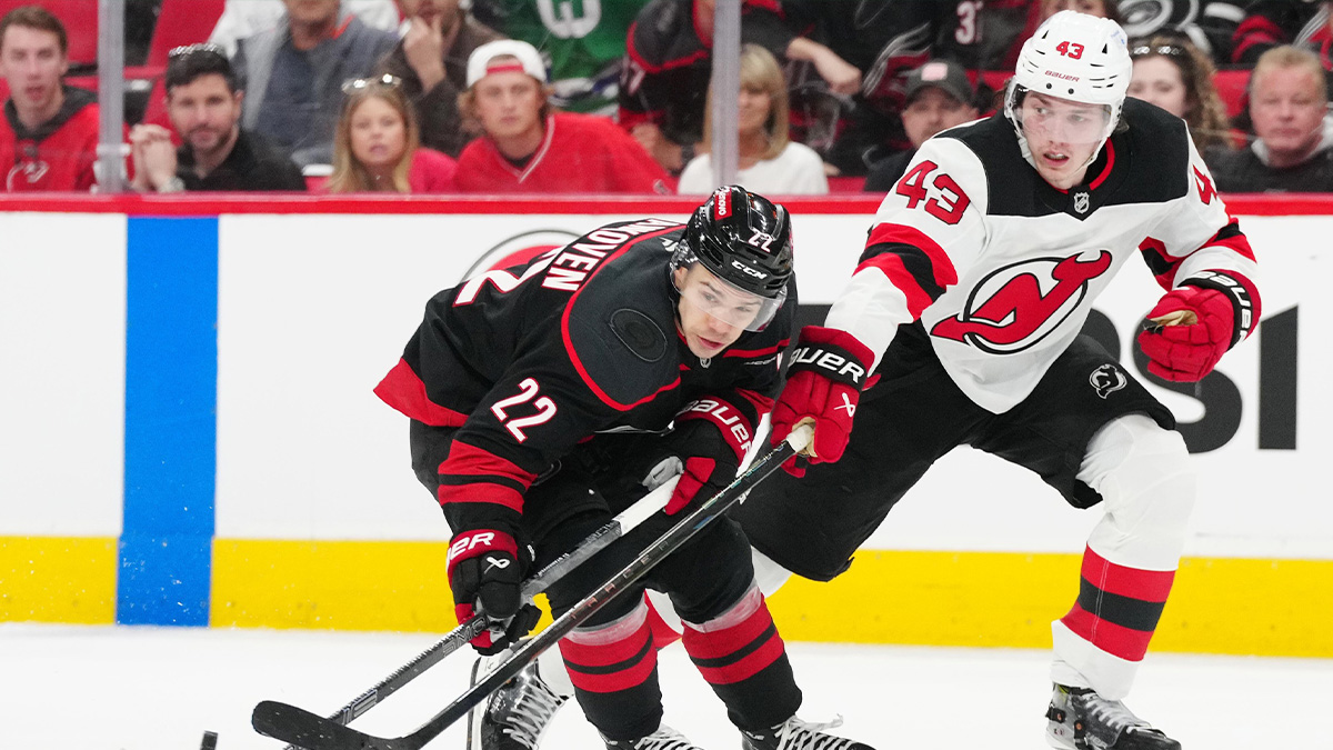 Carolina Hurricanes center Logan Stankoven (22) battles for the puck against New Jersey Devils defenseman Luke Hughes (43) during the third period of game one of the first round of the 2025 Stanley Cup Playoffs at Lenovo Center.
