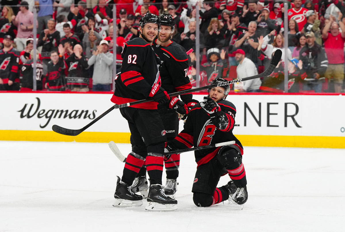 Carolina Hurricanes center Logan Stankoven (22) celebrates his goal with Carolina Hurricanes center Jesperi Kotkaniemi (82) and Carolina Hurricanes defenseman Jaccob Slavin (74) against the New York Islanders during the first period at Lenovo Center.
