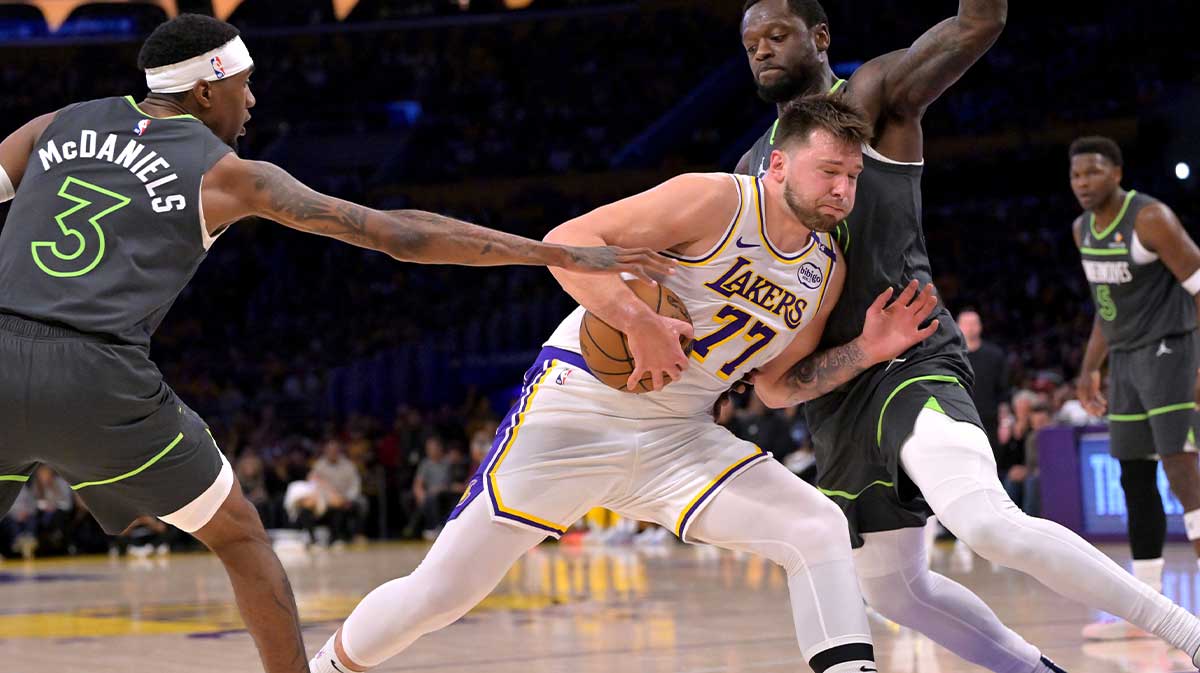 Los Angeles Lakers guard Luka Doncic (77) is defended by Minnesota Timberwolves forward Jaden McDaniels (3) and forward Jaden McDaniels (3) as he drives to the basket in the first quarter at Crypto.com Arena.
