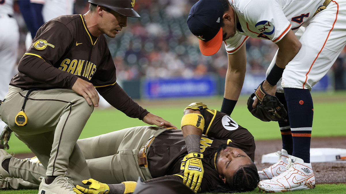 San Diego Padres first base coach David Macias (46) and Houston Astros second baseman Mauricio Dubon (14) check on San Diego Padres designated hitter Luis Arraez (4) as he lies on the field after colliding with Houston Astros first baseman Christian Walker (8) (not pictured )on the first base line in the first inning at Daikin Park.