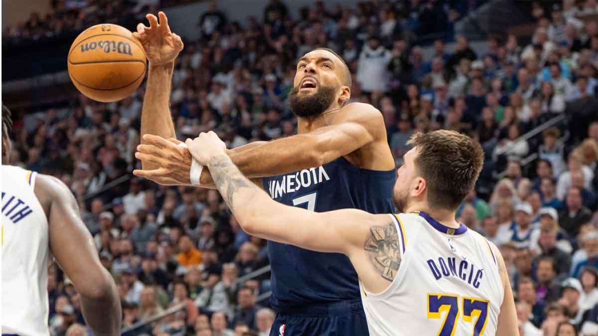 Minnesota Timberwolves center Rudy Gobert (27) goes up for a basket and is fouled by Los Angeles Lakers guard Luka Doncic (77) in the third quarter during game four of first round for the 2025 NBA Playoffs at Target Center.
