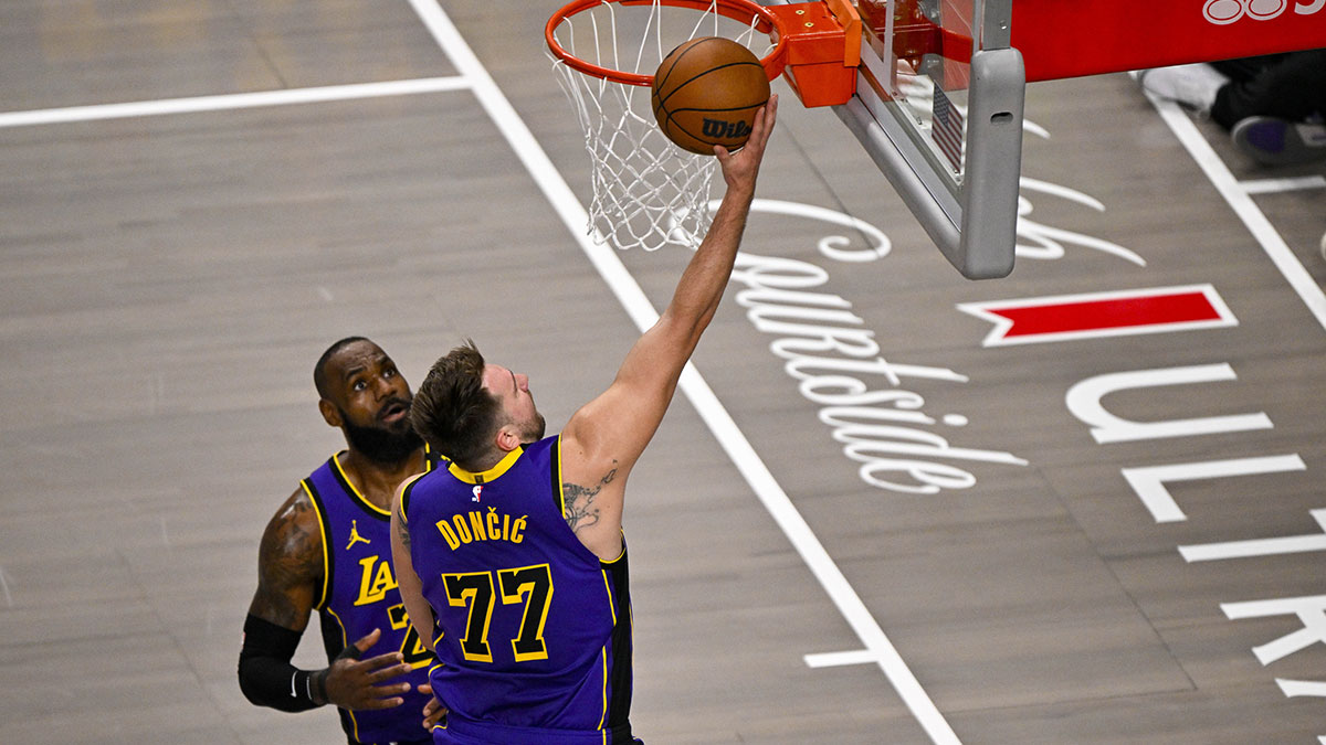 Los Angeles Lakers guard Luka Doncic (77) makes a layup past forward LeBron James (23) during the first quarter against the Dallas Mavericks at the American Airlines Center.
