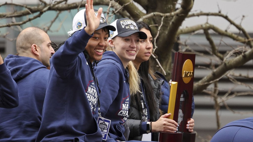 KK Arnold waves to the crowd while Paige Bueckers and Caroline Ducharme look on during the Final Four Champions victory parade and rally.