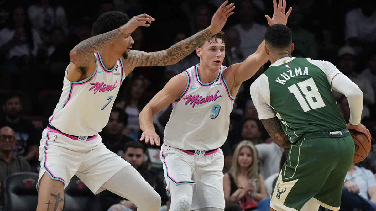 Milwaukee Bucks forward Kyle Kuzma (18) looks to take a shot as Miami Heat and guard Pelle Larsson (9) and center Kel'el Ware (7) defend on the play during the first half at Kaseya Center.