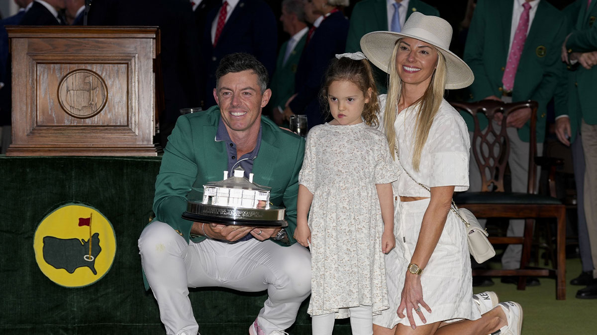Rory McIlroy holds the Masters championship trophy while posing for photographs with his wife, Erica Stoll, and daughter, Poppy, at the green jacket ceremony during the final round of the Masters Tournament at Augusta National Golf Club.