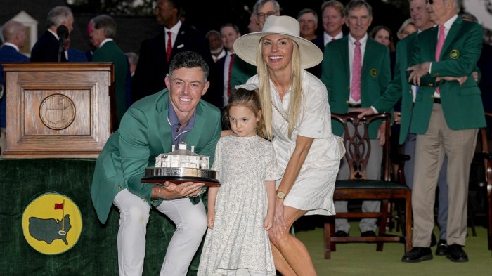 Rory McIlroy holds the Masters championship trophy while posing for photographs with his wife, Erica Stoll, and daughter, Poppy, at the green jacket ceremony during the final round of the Masters Tournament at Augusta National Golf Club