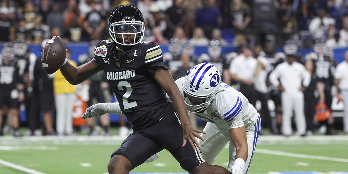 Colorado Buffaloes quarterback Shedeur Sanders (2) attempts to avoid a tackle by Brigham Young Cougars safety Raider Damuni (3) during the second quarter at Alamodome.