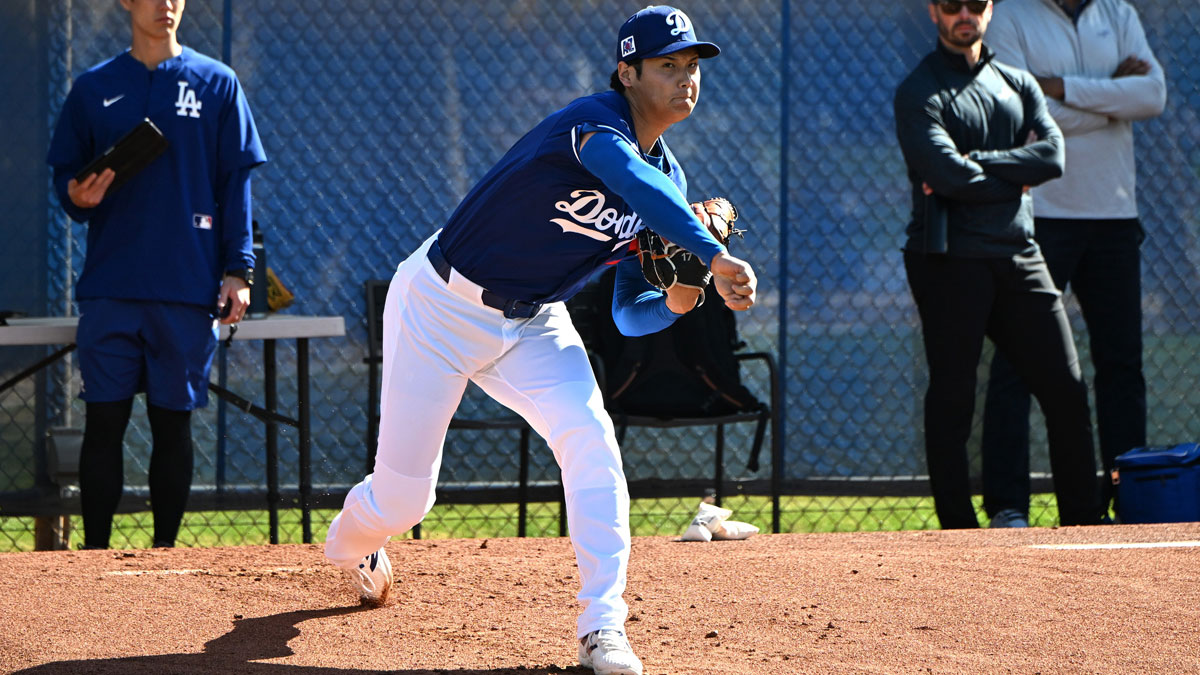 Los Angeles Dodgers translator Will Ireton, left, and Executive Vice President and General Manager Brandon Gomes look on as two-way player Shohei Ohtani (17) throws during a spring training bullpen session at Camelback Ranch.