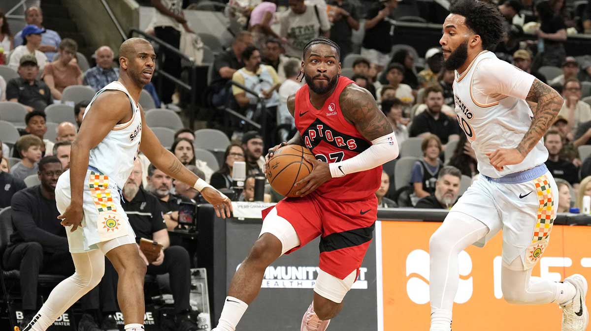 Toronto Raptors guard Jamal Shead (23) drives to the basket between San Antonio Spurs forward Julian Champagnie (30) and guard Chris Paul (3) during the first half at Frost Bank Center.