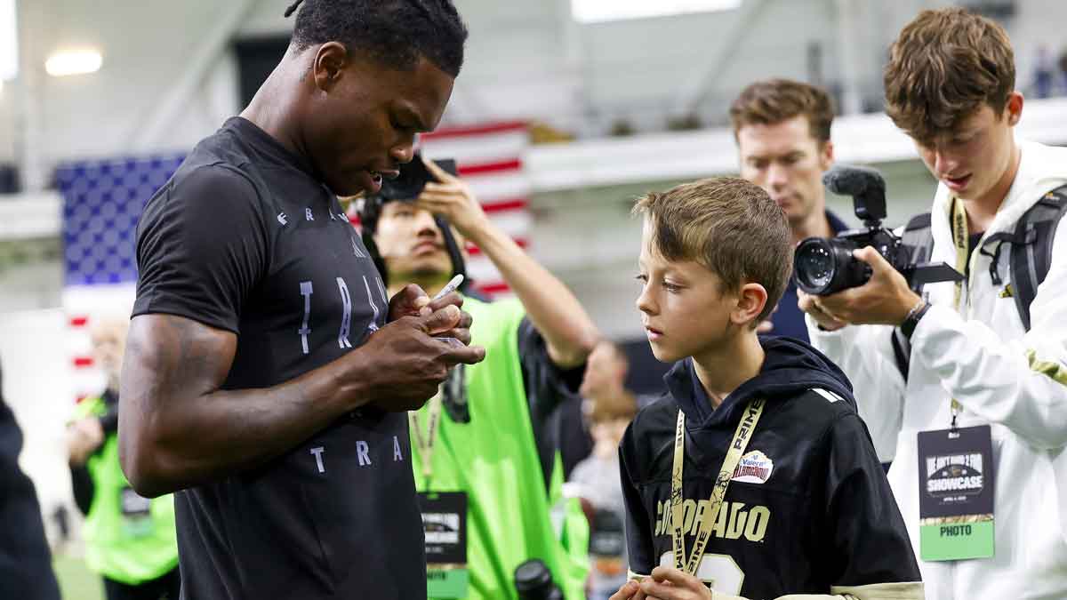 Colorado Buffaloes wide receiver Travis Hunter (12) signs a trading card for a young fan after the University of Colorado NFL Showcase at the CU Indoor Practice Facility.
