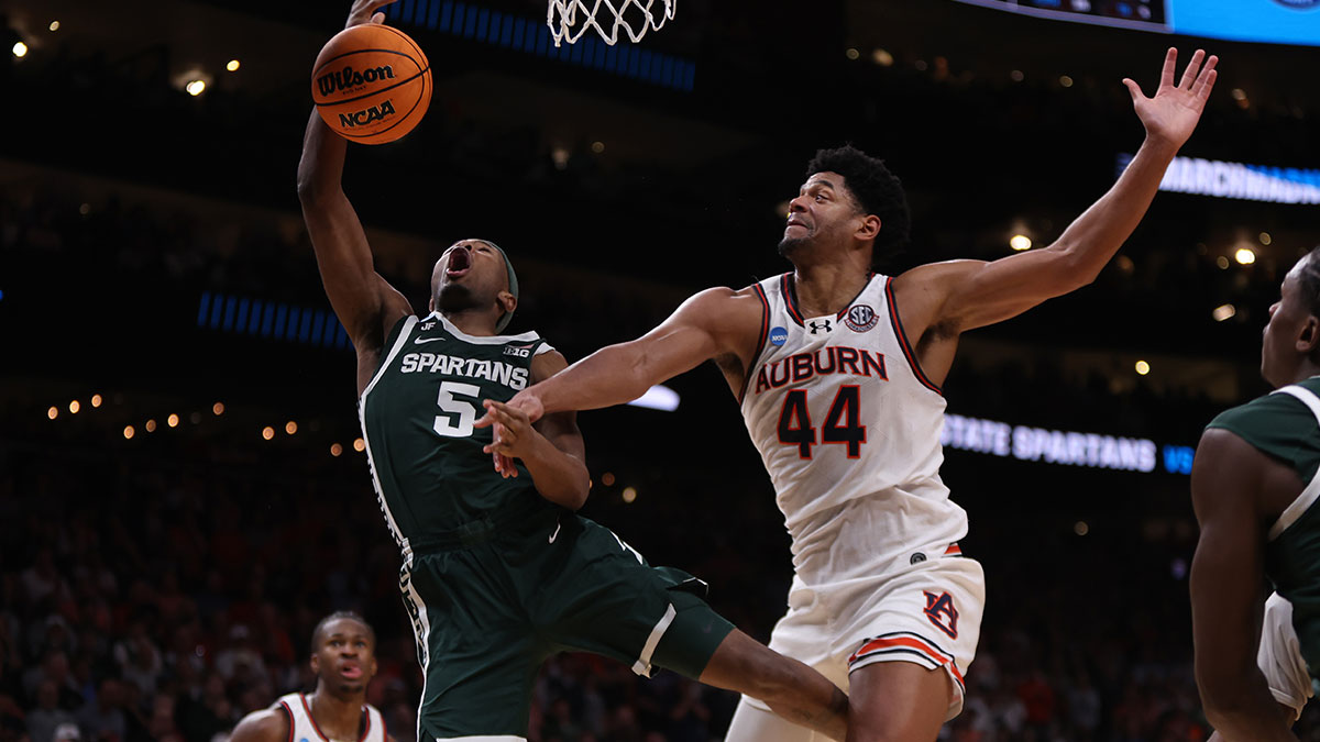 Michigan State Spartans guard Tre Holloman (5) drives against Auburn Tigers center Dylan Cardwell (44) during the second half in the South Regional final of the 2025 NCAA tournament at State Farm Arena.