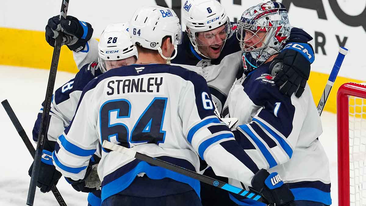 Winnipeg Jets goaltender Eric Comrie (1) celebrates with Winnipeg Jets defenseman Colin Miller (6) after defeating the Vegas Golden Knights 4-0 at T-Mobile Arena.