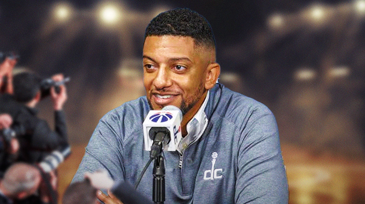 Wizards GM Will Dawkins sits at podium with microphone