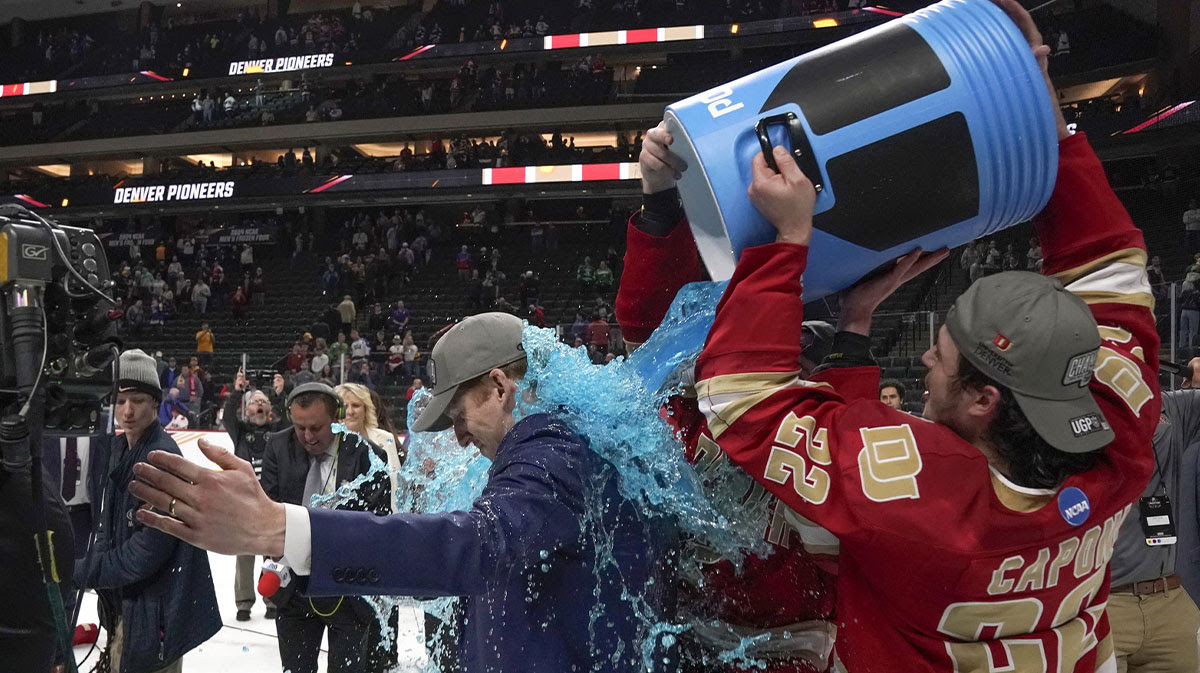 Denver Pioneers forward Connor Caponi (22) dumps blue Powerade on head coach David Carle after defeating the Boston College Eagles for the national championship at the 2024 Frozen Four college ice hockey tournament at Xcel Energy Center.