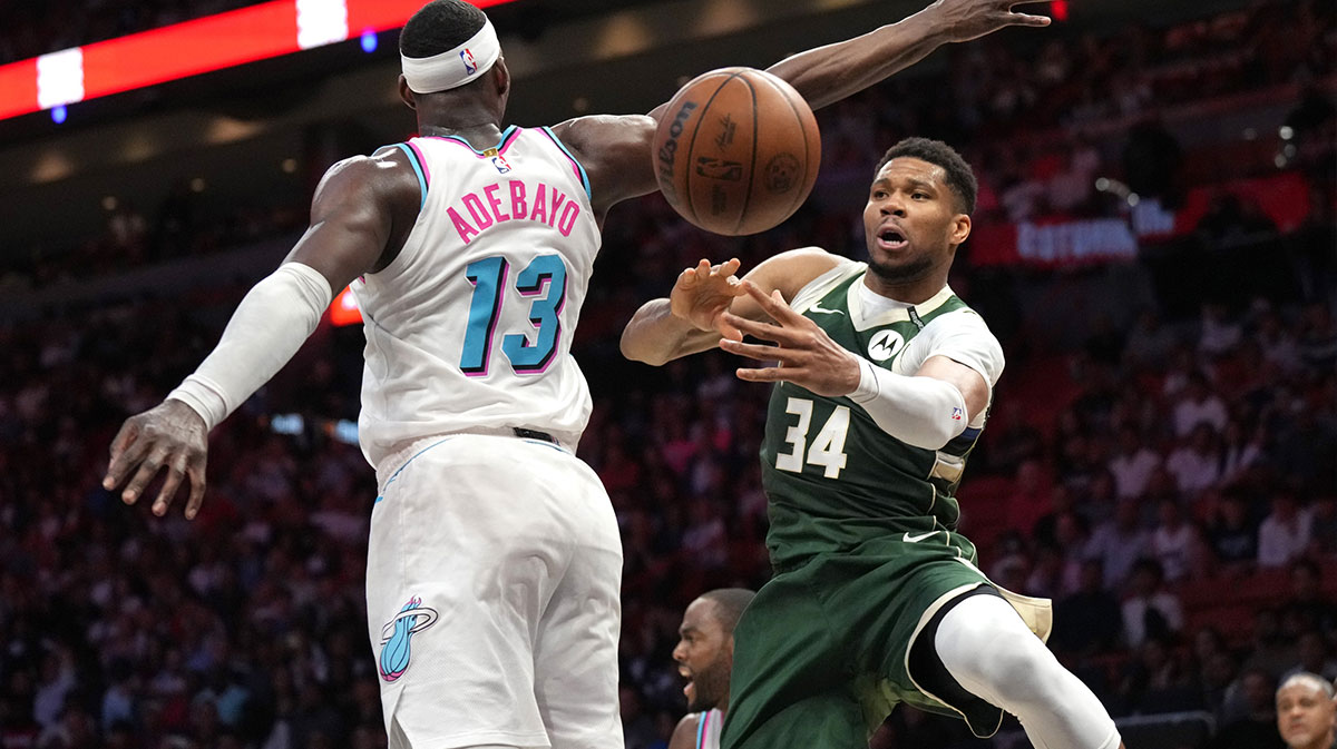 Milwaukee Bucks forward Giannis Antetokounmpo (34) passes the ball under the arm of Miami Heat center Bam Adebayo (13) during overtime at Kaseya Center.