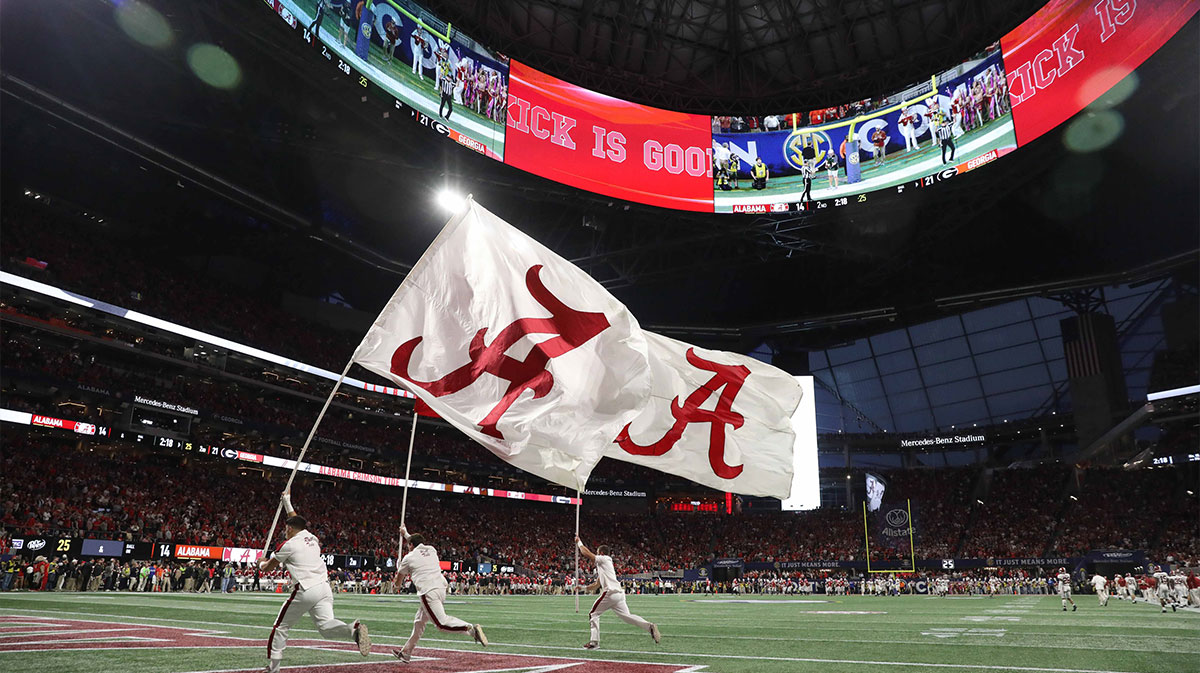 The Alabama Crimson Tide cheerleaders run with flags after an Alabama touchdown during the game against the Georgia Bulldogs in the SEC championship game at Mercedes-Benz Stadium.