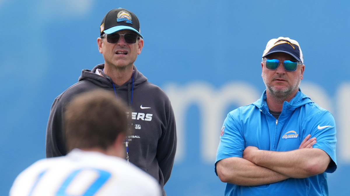Los Angeles Chargers coach Jim Harbaugh (left) and general manager Joe Hortiz watch as quarterback Justin Herbert takes the snap during offseason workouts.