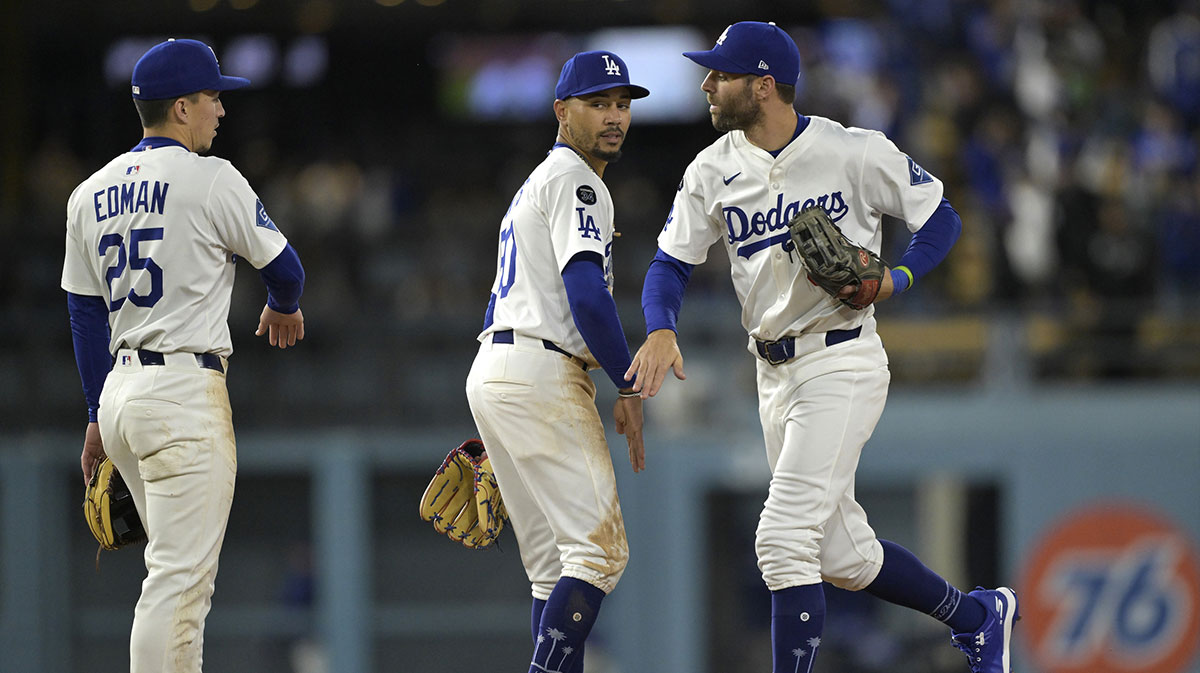 Los Angeles Dodgers second baseman Tommy Edman (25), shortstop Mookie Betts (50) and left fielder Chris Taylor (3) head off the field following the game against the Colorado Rockies at Dodger Stadium.