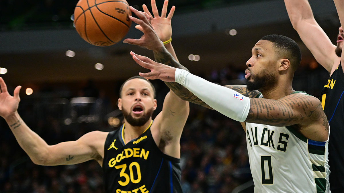 Milwaukee Bucks guard Damian Lillard (0) passes the ball away from Golden State Warriors guard Stephen Curry (30) in the fourth quarter at Fiserv Forum.