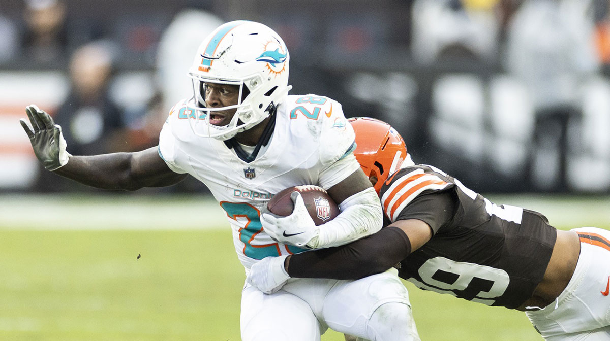 Miami Dolphins running back De'Von Achane (28) runs the ball as Cleveland Browns cornerback Cameron Mitchell (29) tackles him during the first quarter at Huntington Bank Field.