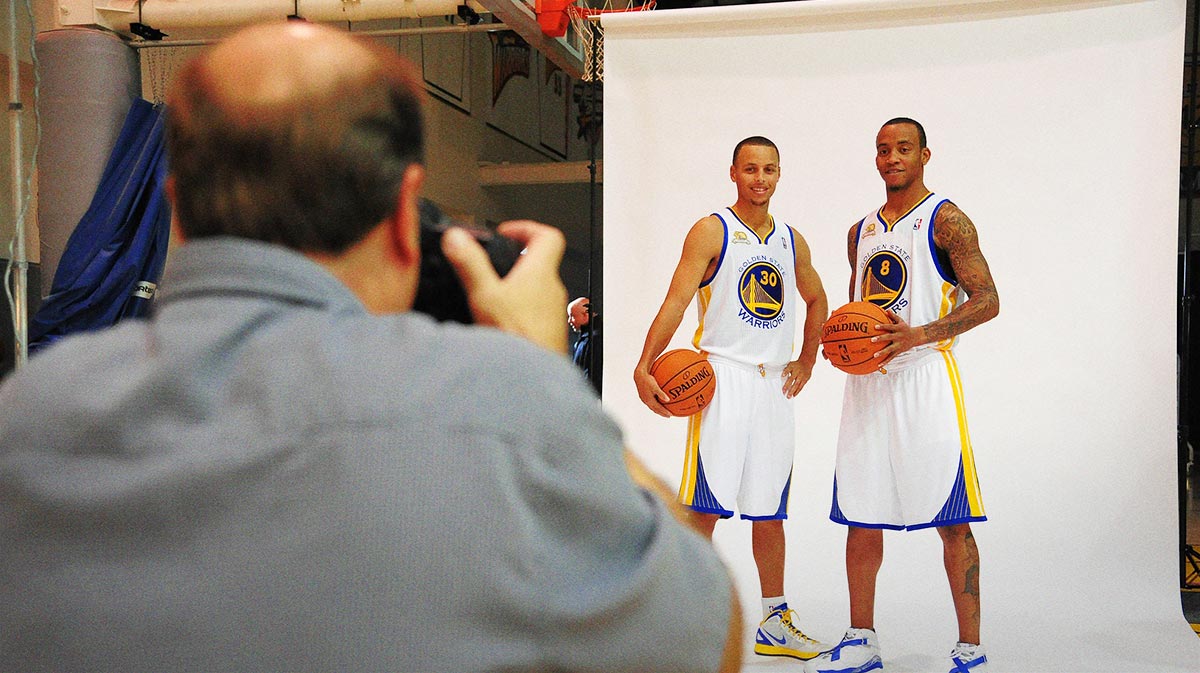 A NBA team photographer (left) photographs Golden State Warriors point guard Stephen Curry (center) and shooting guard Monta Ellis (right) during media day at the Golden State Warriors Practice Facility.
