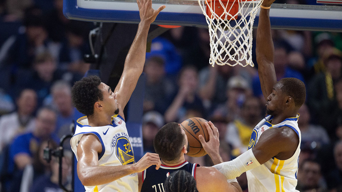 Golden State Warriors forwards Trayce Jackson-Davis (32) and Jonathan Kuminga (00) foul Los Angeles Clippers center Ivica Zubac (40) on a shot at the basket during the first quarter at Chase Center.