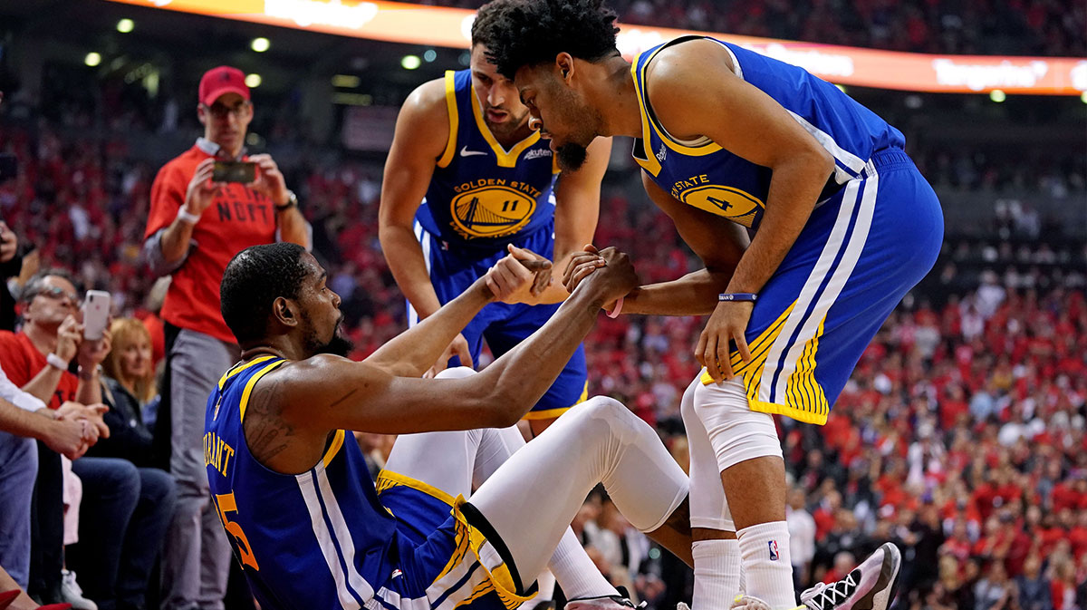 Golden State Warriors forward Kevin Durant (35) is helped up by guard Quinn Cook (4) and guard Klay Thompson (11) after an apparent injury during the second quarter in game five of the 2019 NBA Finals against the Toronto Raptors at Scotiabank Arena.