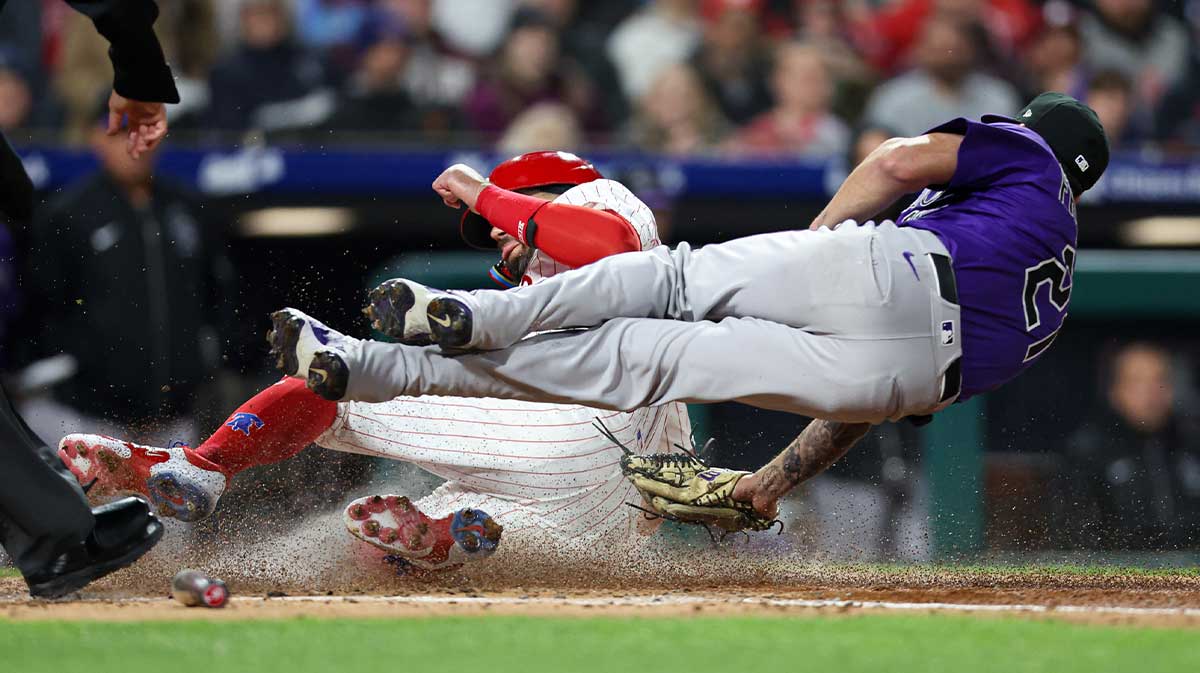 Philadelphia Phillies designated hitter Kyle Schwarber (12) slides home for a run past the tag attempt of Colorado Rockies pitcher Kyle Freeland (21) during the fourth inning at Citizens Bank Park.