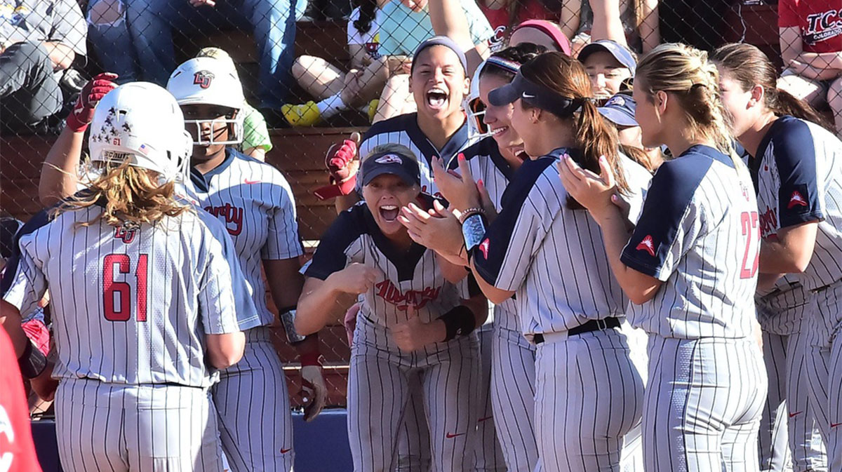 Liberty players gather to welcome Amber Bishop home after Bishop hit a two-run homer in the bottom of the sixth inning to give the Flames an 8-6 lead over Texas-Arlington in a National Invitational Softball Championship game. Texas-Arlington rallied in the seventh for a 9-8 win in the game, played at Triple Crown Sports' Colorado Field.