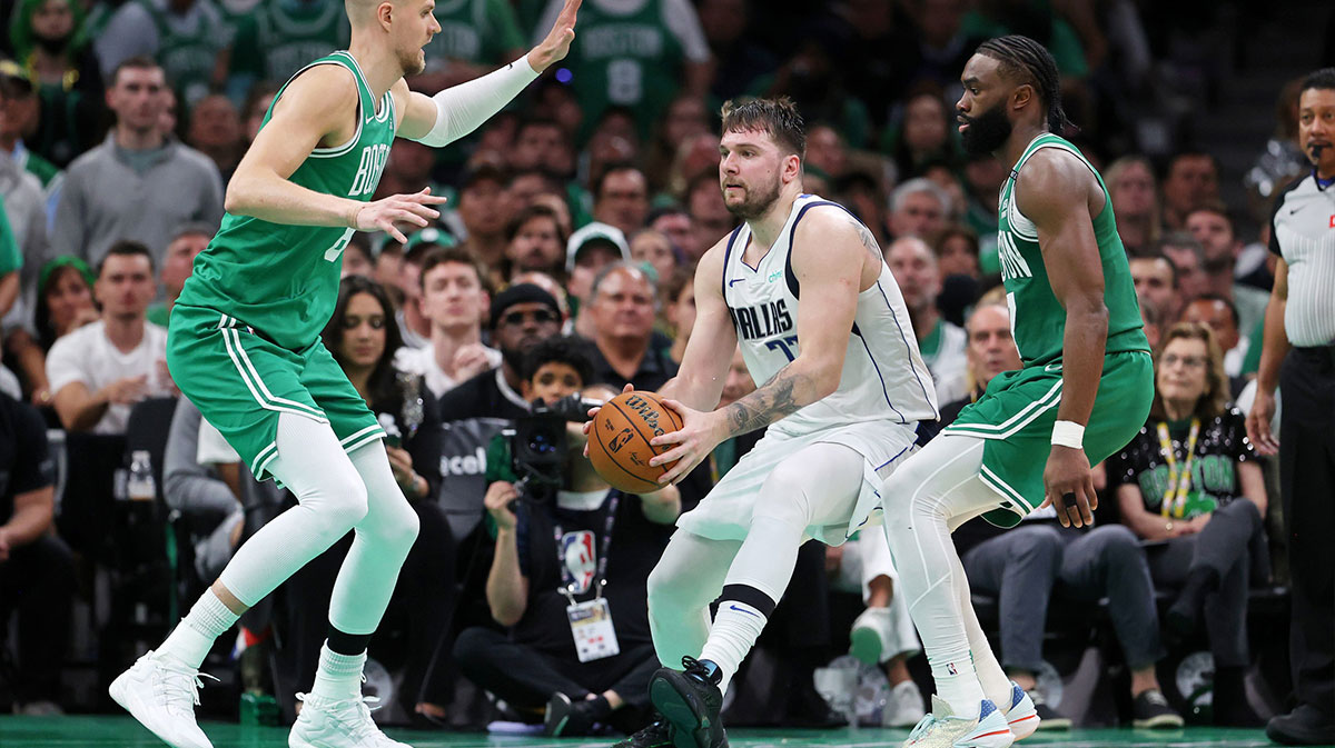 Dallas Mavericks guard Luka Doncic (77) controls the ball against Boston Celtics center Kristaps Porzingis (8) and guard Jaylen Brown (right) during the fourth quarter in game five of the 2024 NBA Finals at TD Garden.