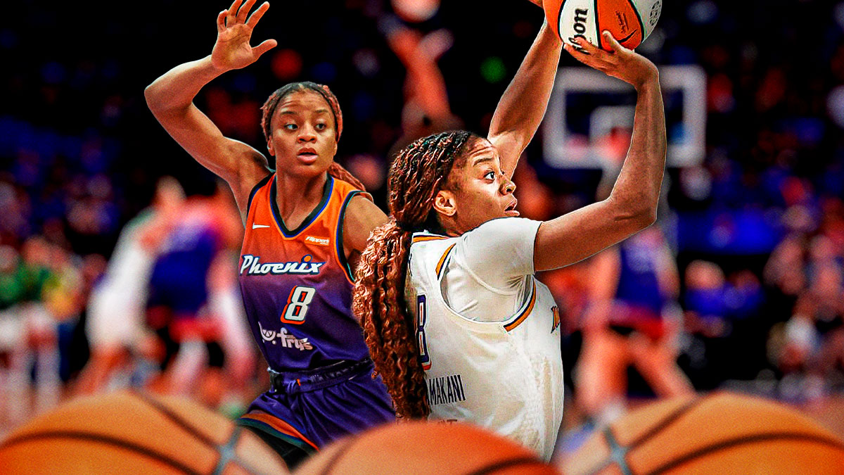 Monique Akoa Makani in a Phoenix Mercury while also in a defensive stance, and she's also shooting a 3-pointer.