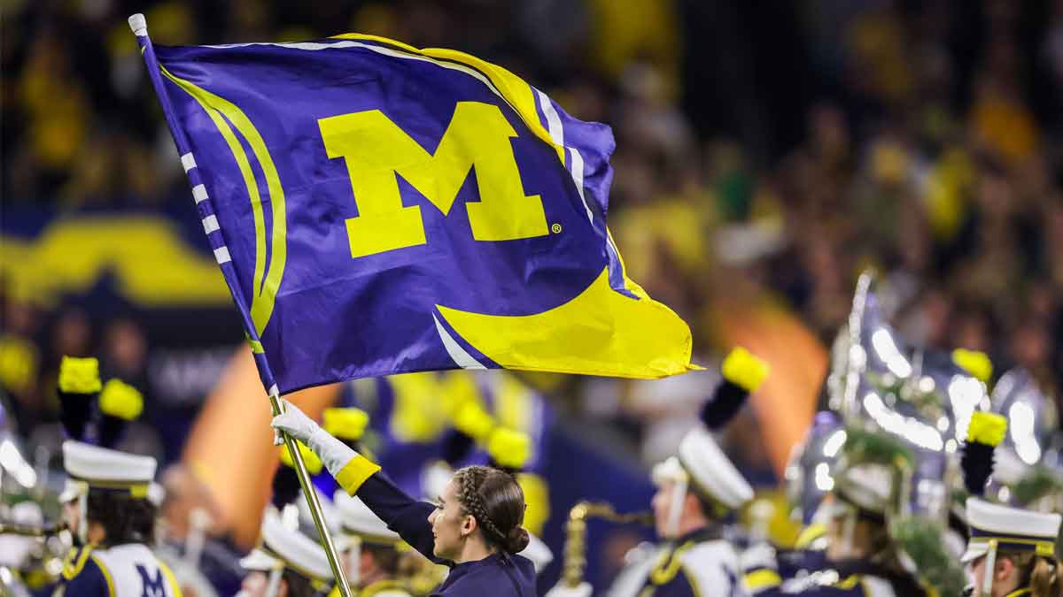 A Michigan Wolverines marching band color guard flag member carries the Michigan flag across the field before the Wolverines played against the Washington Huskies in the 2024 College Football Playoff national championship game at NRG Stadium.