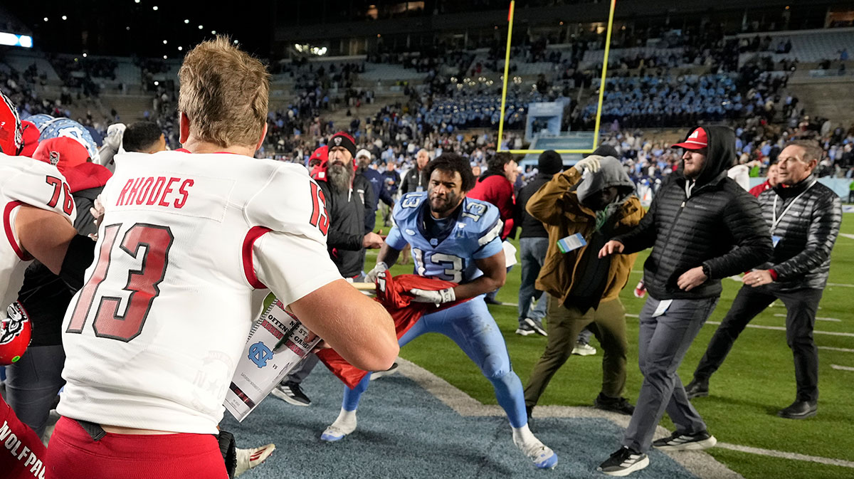 North Carolina Tar Heels players and North Carolina State Wolfpack players fight as State tries to put a Wolfpack flag at midfield after the game at Kenan Memorial Stadium.
