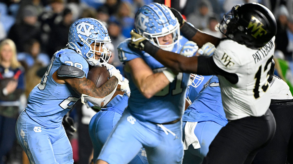 North Carolina Tar Heels running back Omarion Hampton (28) runs as tight end John Copenhaver (81) blocks and Wake Forest Demon Deacons defensive back Davaughn Patterson (13) defends in the fourth quarter at Kenan Memorial Stadium.