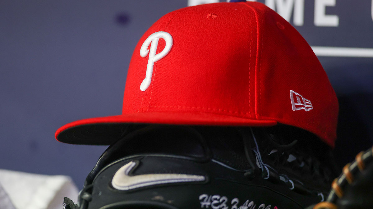 A detailed view of a Philadelphia Phillies hat and glove on the bench against the Atlanta Braves in the seventh inning at Truist Park.