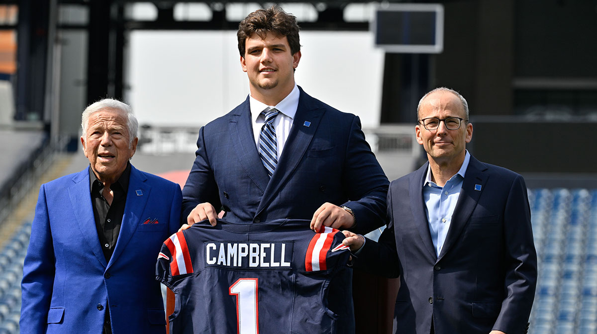 New England Patriots first round draft pick Will Campbell is presented with a ceremonial first round jersey by team owner Robert Kraft (l) and team president Jonathan Kraft (r) at a press conference on the game field at Gillette Stadium.