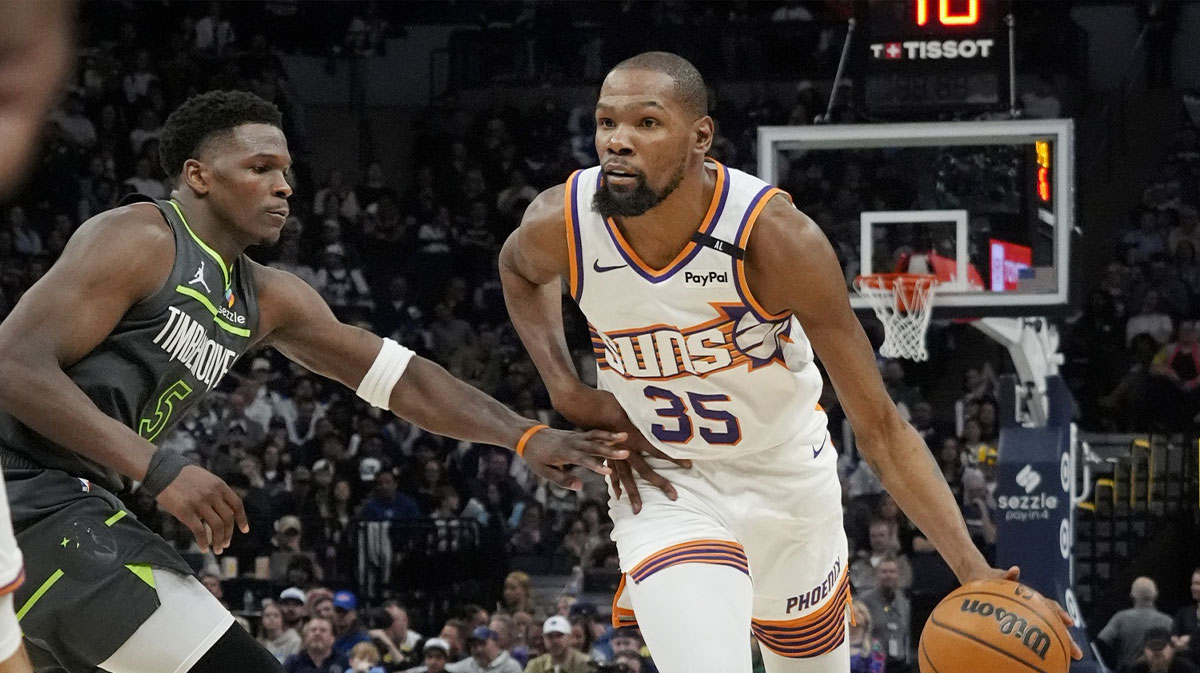 Suns forward Kevin Durant (35) brings the ball up as Minnesota Timberwolves guard Anthony Edwards (5) defends him in the fourth quarter at Target Center with ESPN's Brian Windhorst in the background