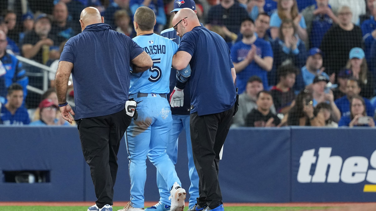 Toronto Blue Jays centre fielder Daulton Varsho (5) is helped off the field after grabbing his left leg after rounding second base against the Athletics during the third inning at Rogers Centre.