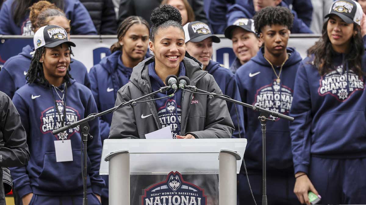 UConn student-athlete Azzi Fudd addresses the crowd while her teammates UConn student-athletes Paige Bueckers, KK Arnold, Sarah Strong and Ayanna Patterson look on during the Final Four champions victory parade and rally outside of the XL Center in Hartford, CT