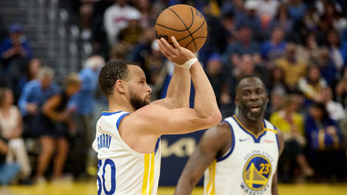 Warriors guard Stephen Curry (30) shoots the ball as Golden State Warriors forward Draymond Green (23) looks on against the LA Clippers during the second quarter at Chase Center