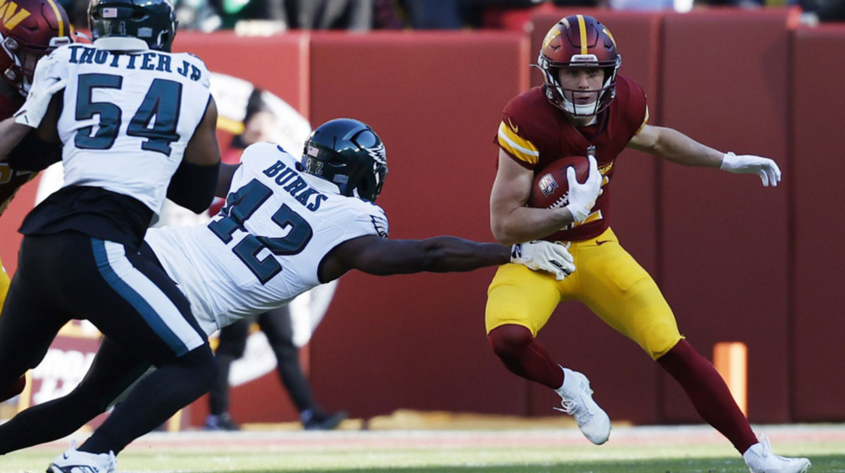 Washington Commanders wide receiver Luke McCaffrey (12) returns a kickoff as Philadelphia Eagles linebacker Oren Burks (42) defends during the first quarter at Northwest Stadium.